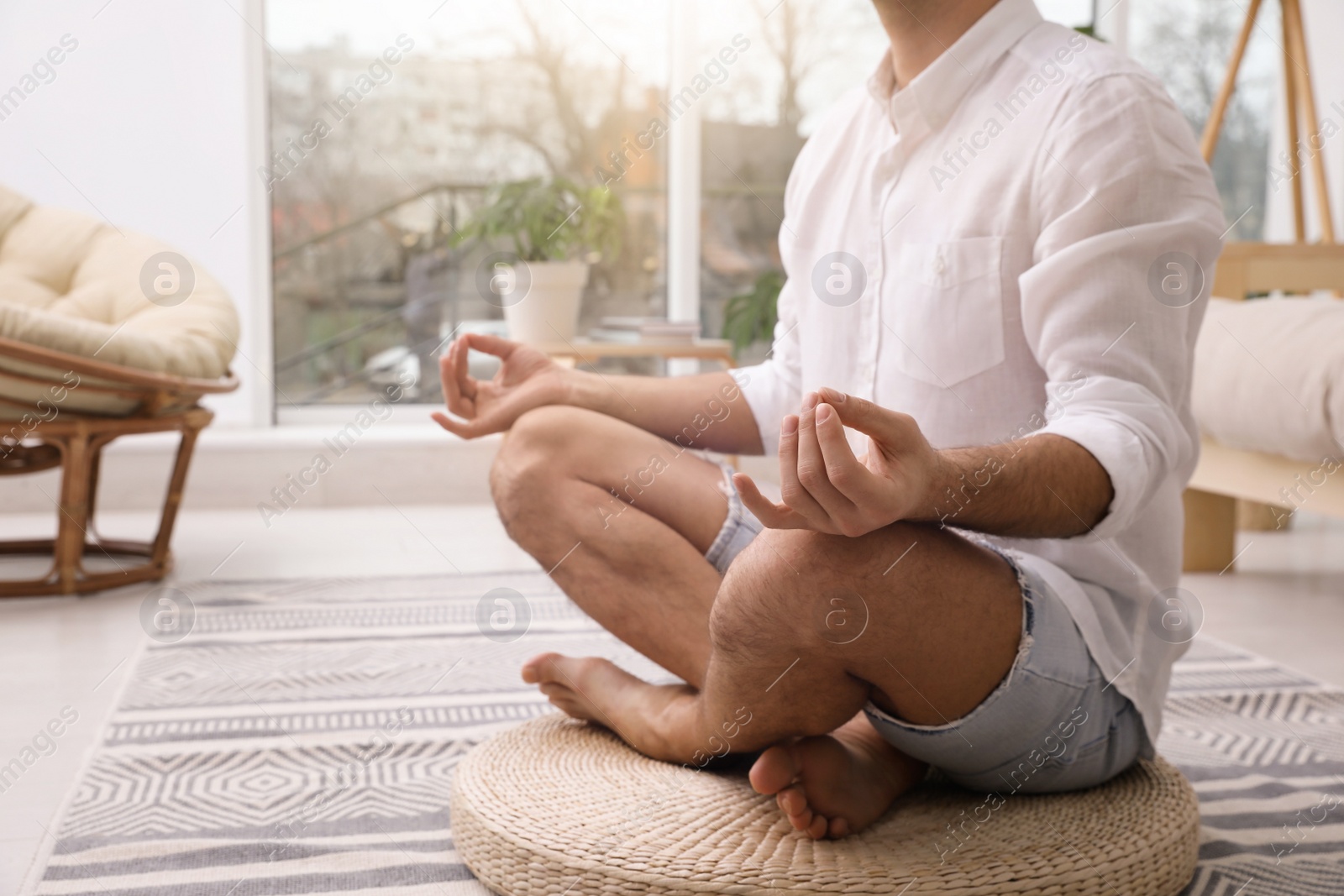 Photo of Man meditating on wicker mat at home, closeup