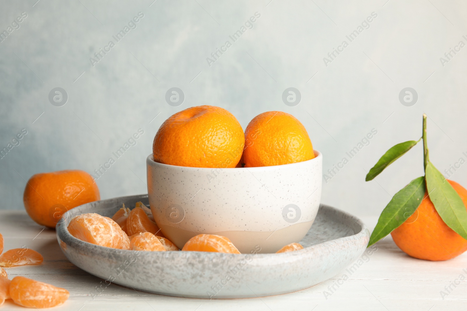 Photo of Plate and bowl with ripe tangerines on table