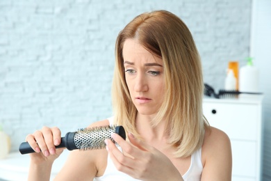 Photo of Young woman with hair loss problem at home