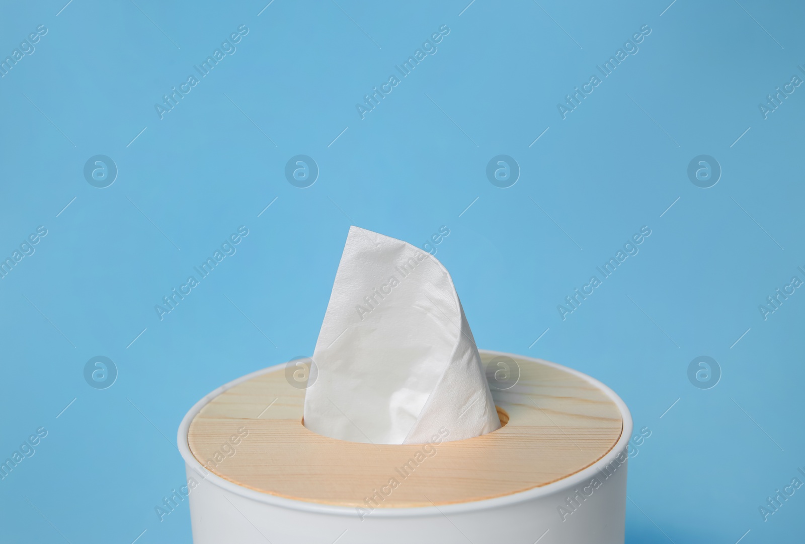 Photo of Holder with paper tissues on light blue background, closeup