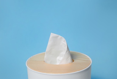 Photo of Holder with paper tissues on light blue background, closeup