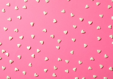 Photo of White heart shaped sprinkles on pink background, flat lay