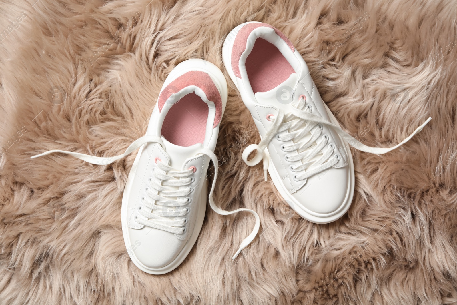 Photo of Pair of stylish shoes with laces on faux fur, flat lay