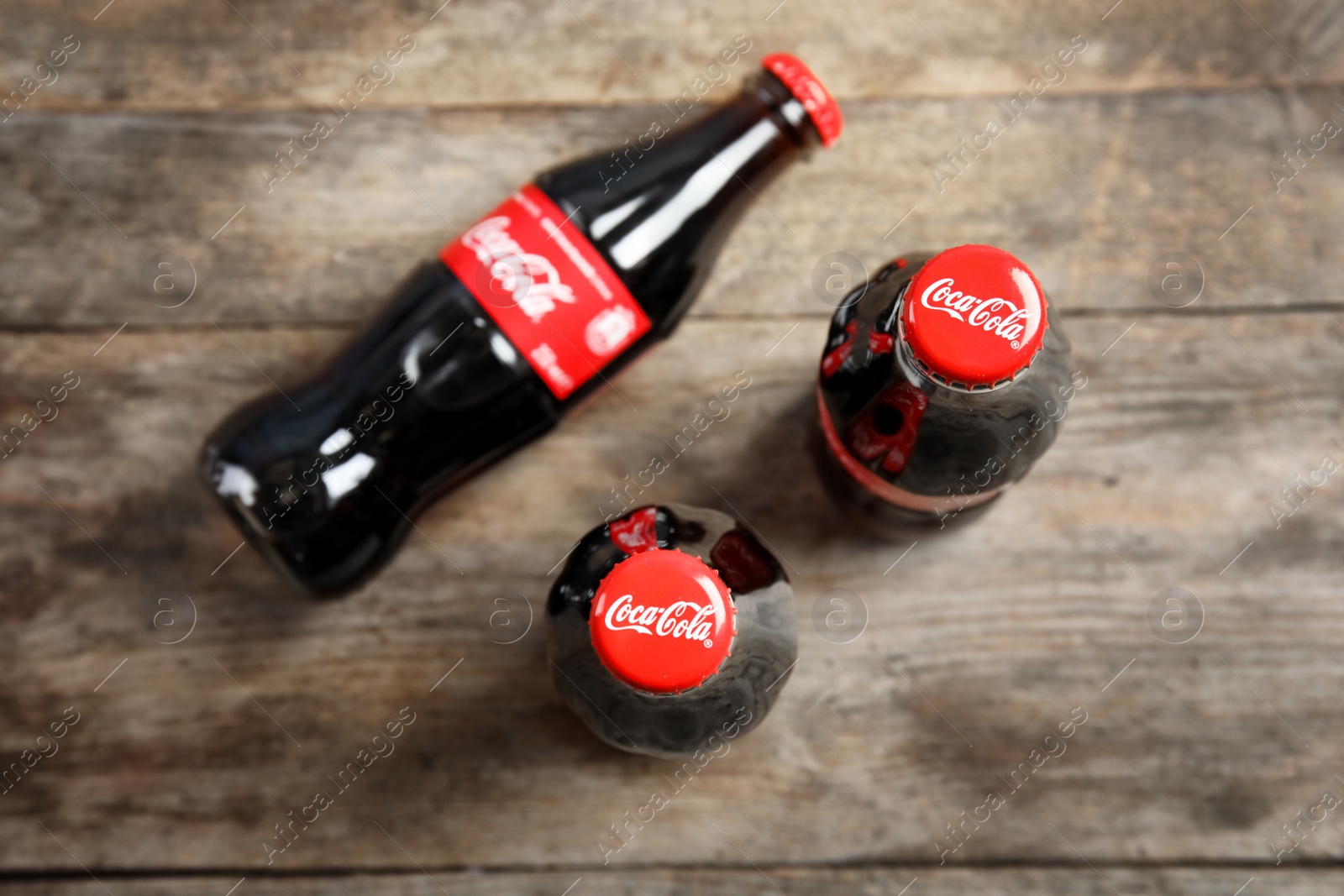 Photo of MYKOLAIV, UKRAINE - NOVEMBER 15, 2018: Bottles of Coca Cola on wooden background, top view