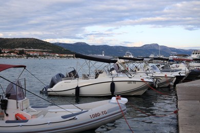 Photo of Trogir, Croatia - September 24, 2023: Picturesque view of moored boats, mountains and sea on cloudy day