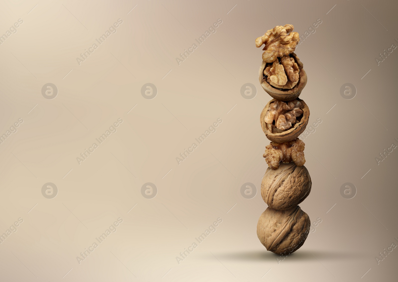 Image of Stacked walnuts on light brown gradient background, space for text