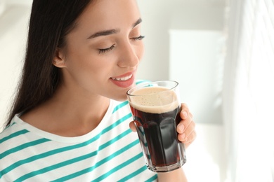 Beautiful woman with cold kvass indoors. Traditional Russian summer drink