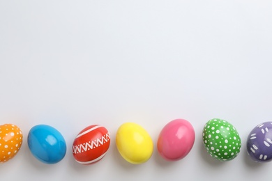 Photo of Decorated Easter eggs and space for text on white background, top view