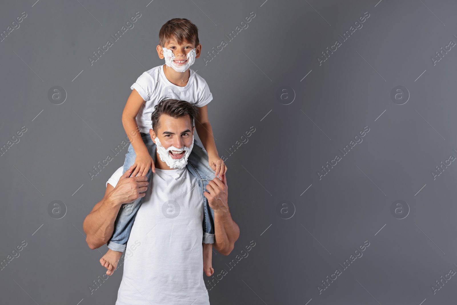 Photo of Father and son with shaving foam on faces against color background. Space for text