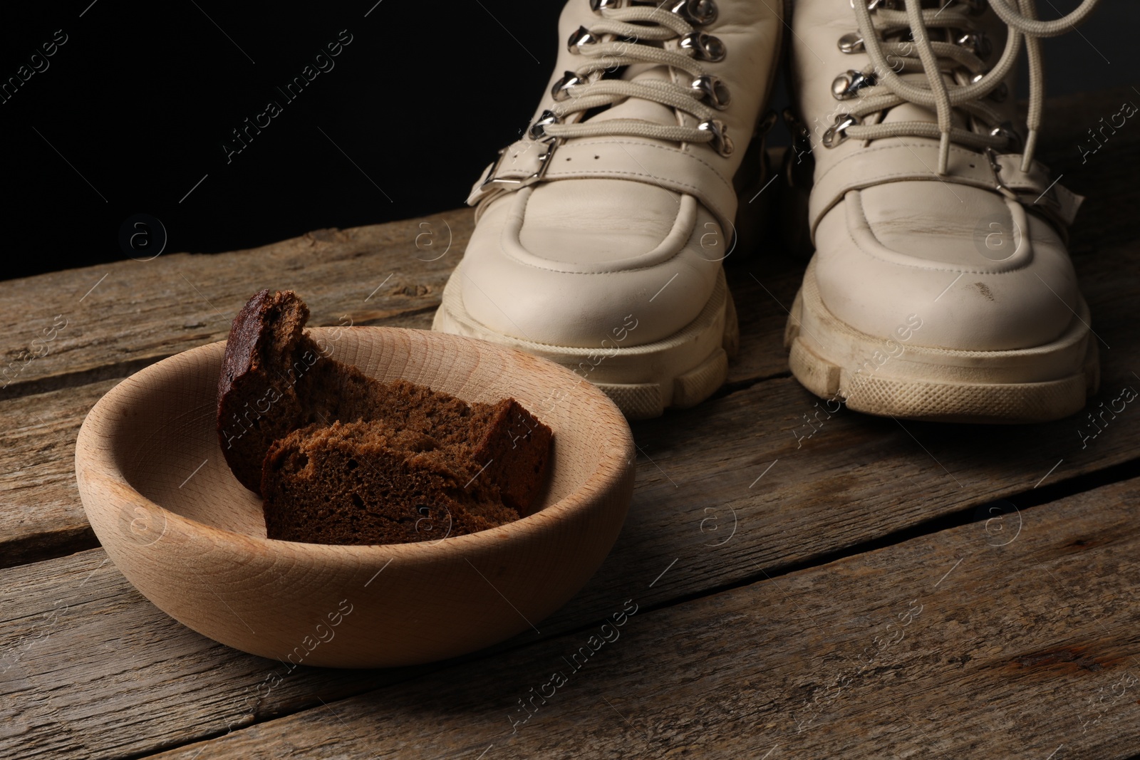 Photo of Poverty. Old boots and pieces of bread on wooden table