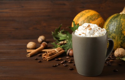 Photo of Cup with tasty pumpkin spice latte on wooden table, space for text
