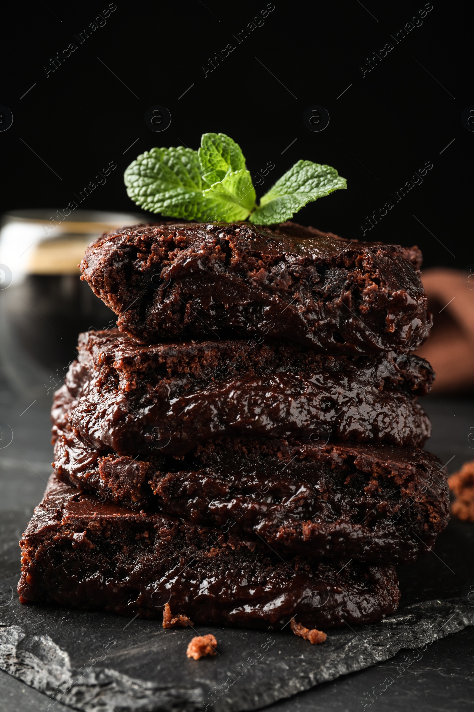 Photo of Delicious chocolate brownies with fresh mint on black table