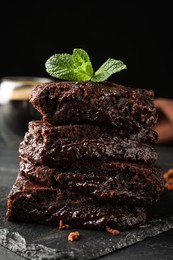 Delicious chocolate brownies with fresh mint on black table