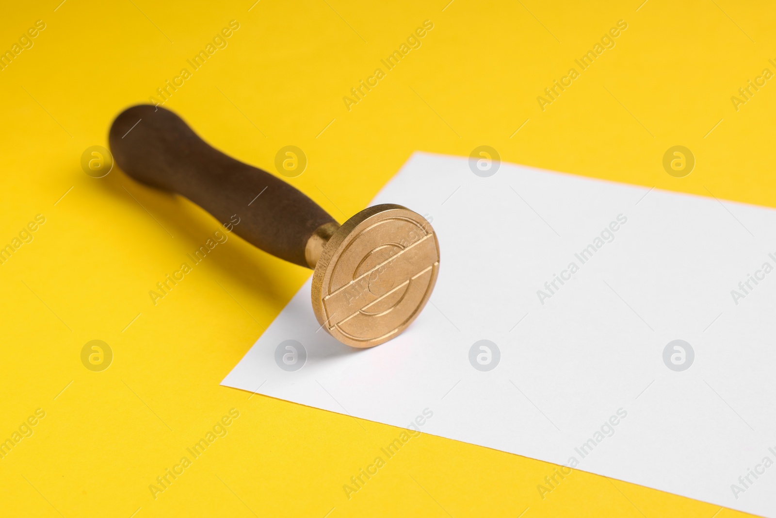 Photo of One stamp tool and sheet of paper on yellow background, closeup
