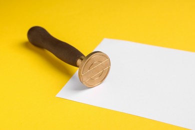 One stamp tool and sheet of paper on yellow background, closeup