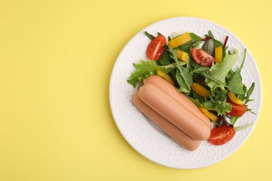 Photo of Delicious boiled sausages with salad on yellow background, top view. Space for text