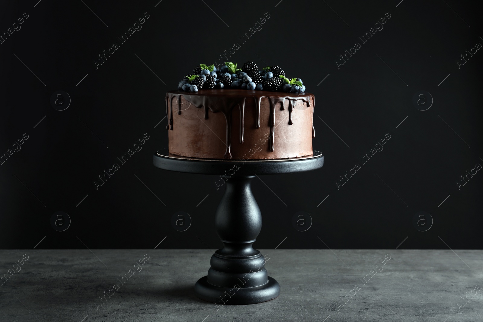 Photo of Fresh delicious homemade chocolate cake with berries on table against dark background