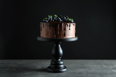 Fresh delicious homemade chocolate cake with berries on table against dark background