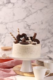 Photo of Delicious cake decorated with sweets and tableware on white table