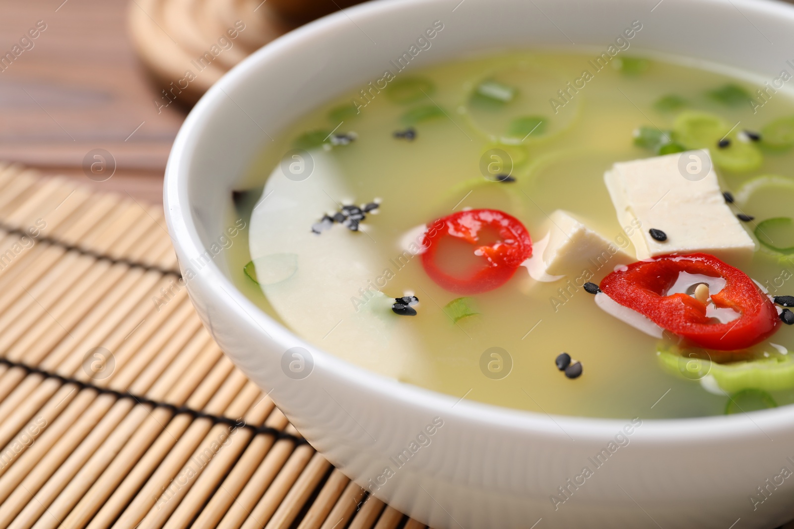 Photo of Bowl of delicious miso soup with tofu on table, closeup