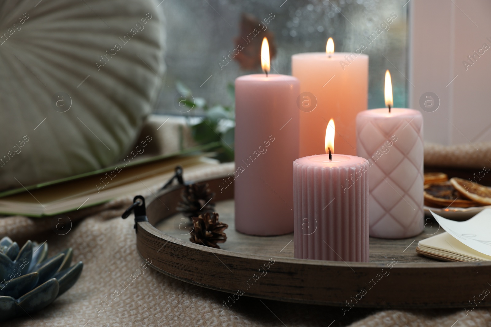 Photo of Tray with burning wax candles and decor on window sill indoors