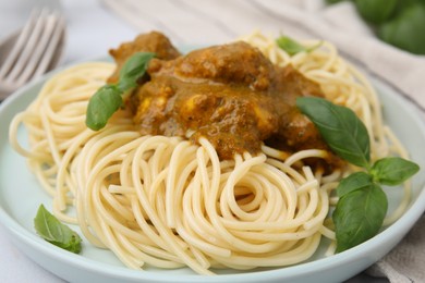 Delicious pasta and chicken with curry sauce served on plate, closeup