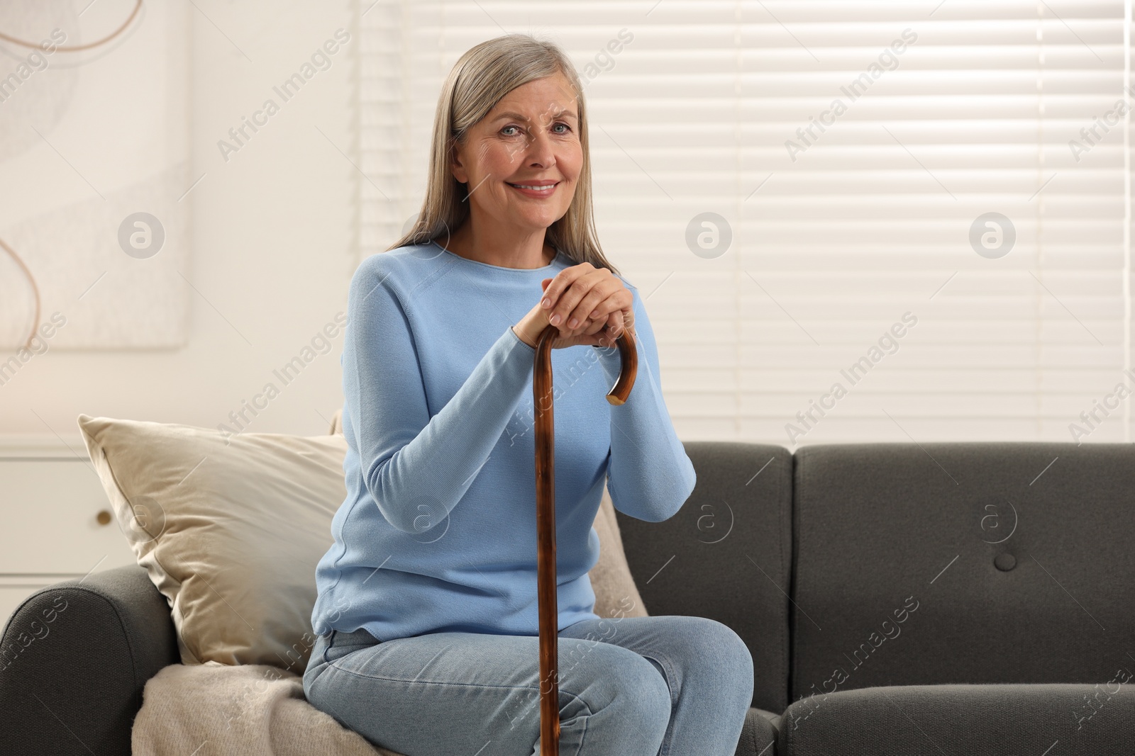 Photo of Mature woman with walking cane on sofa at home