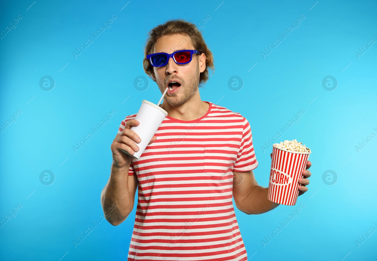 Photo of Emotional man with 3D glasses, popcorn and beverage during cinema show on color background