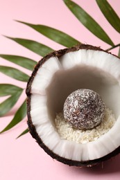 Photo of Composition with delicious vegan candy ball and coconut on pink background