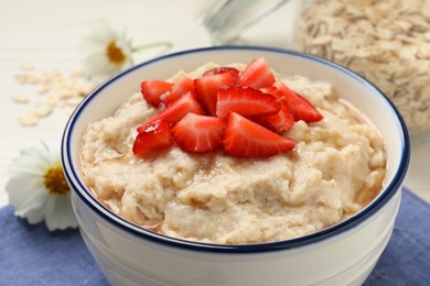 Photo of Tasty oatmeal porridge with strawberries on table, closeup