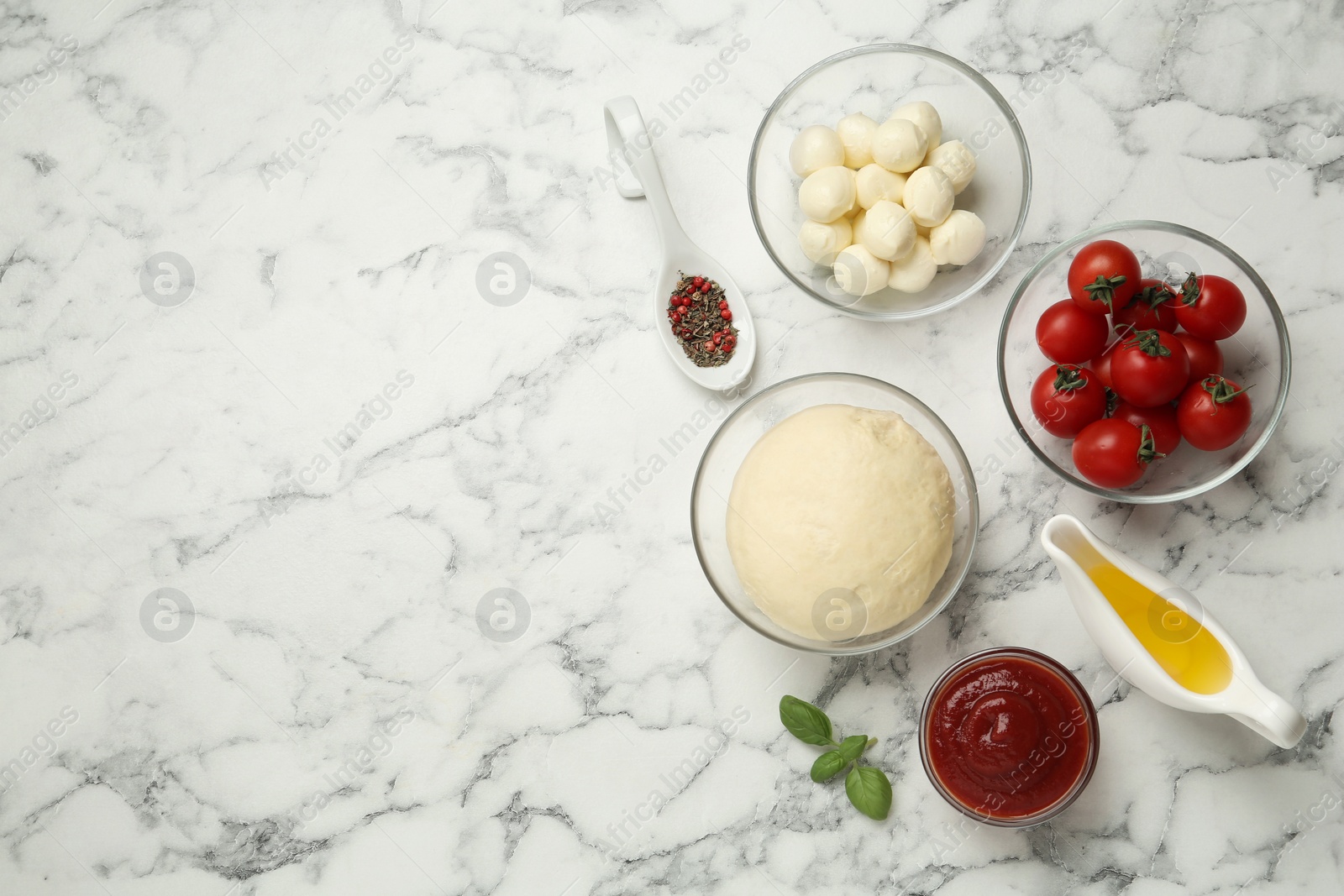 Photo of Raw pizza dough and other ingredients on white marble table, flat lay. Space for text