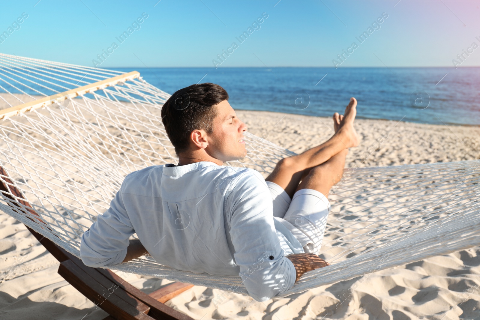 Photo of Man relaxing in hammock on beach. Summer vacation