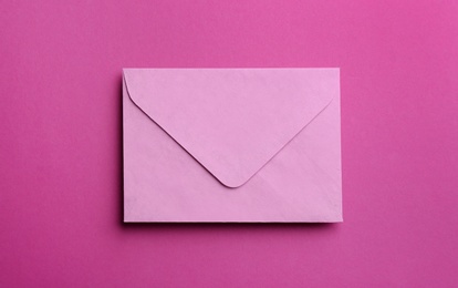 Photo of Pink paper envelope on purple background, top view