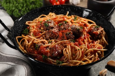 Photo of Delicious pasta with meatballs and tomato sauce on grey table, closeup
