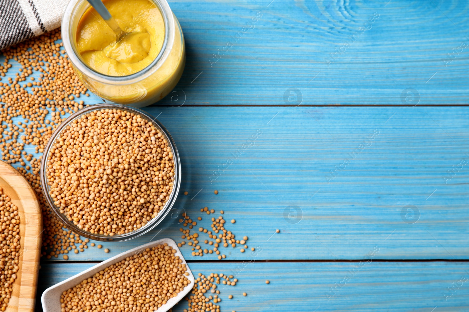 Photo of Flat lay composition with mustard seeds on turquoise wooden table. Space for text