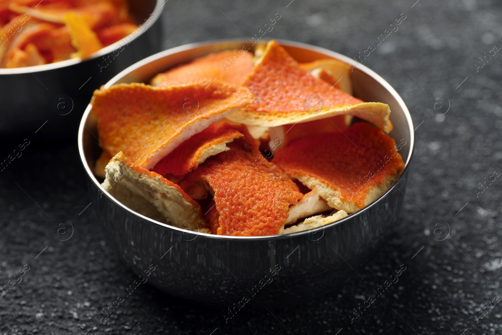 Photo of Bowls with dry orange peels on gray textured table, closeup