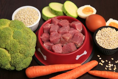 Photo of Raw meat in bowl and healthy products for pet on black background