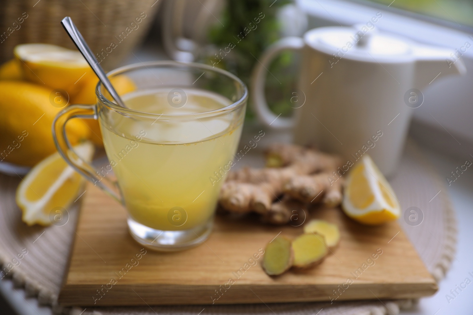 Photo of Glass of aromatic ginger tea and ingredients near window, space for text