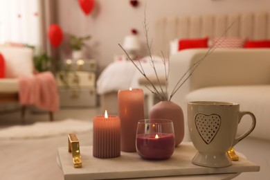 Photo of Burning candles and cup of hot drink on table in room