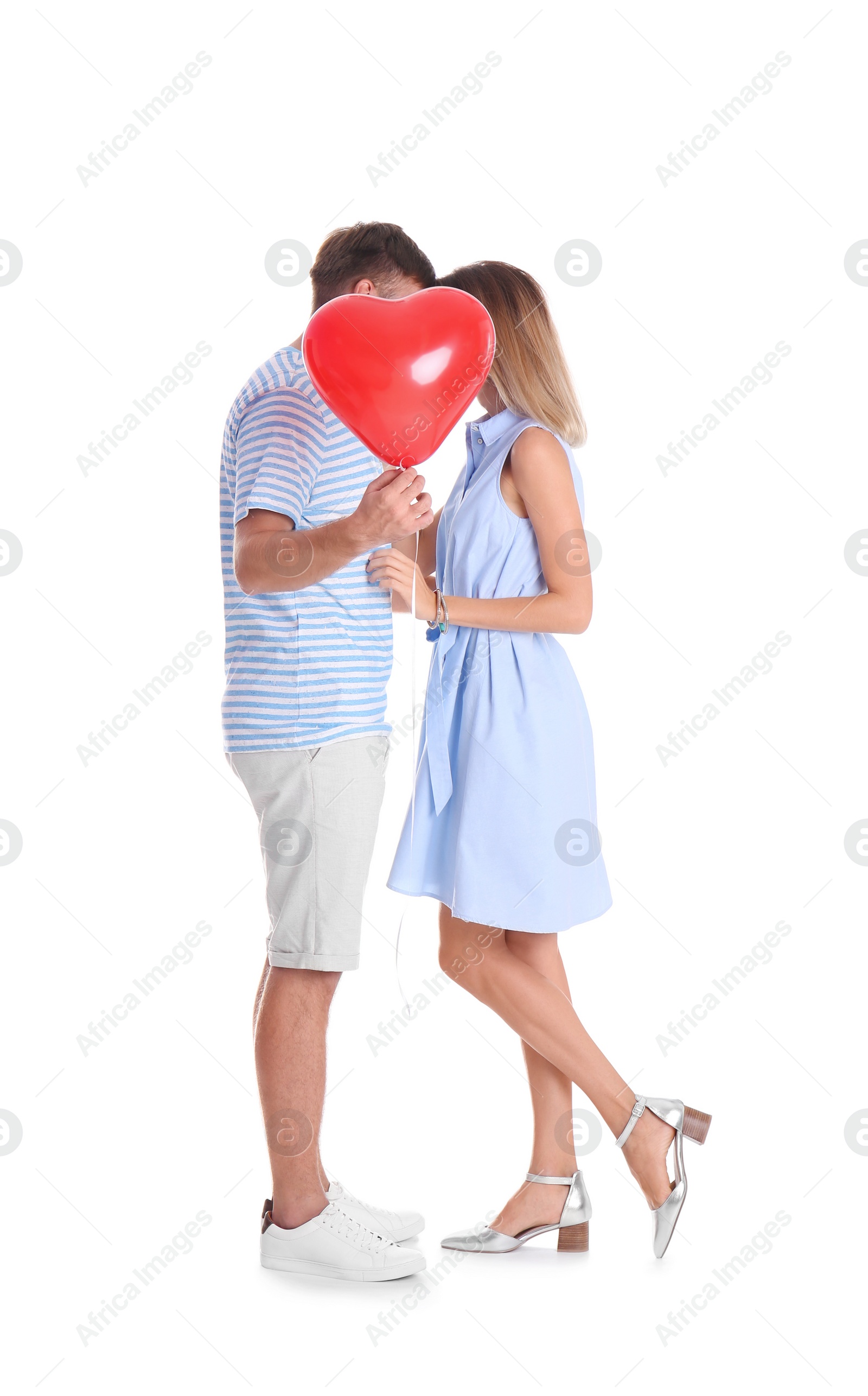 Photo of Young couple hiding behind heart-shaped air balloon on white background. Celebration of Saint Valentine's Day