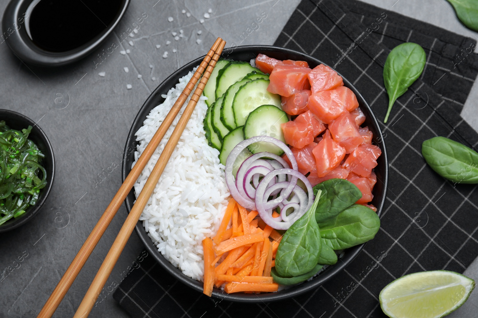 Photo of Delicious poke bowl with salmon and vegetables served on grey table, flat lay