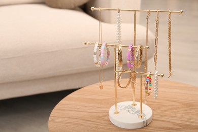 Holder with set of luxurious jewelry on wooden table in living room