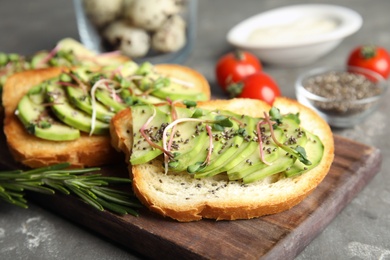 Photo of Tasty toasts with avocado, sprouts and chia seeds on wooden board