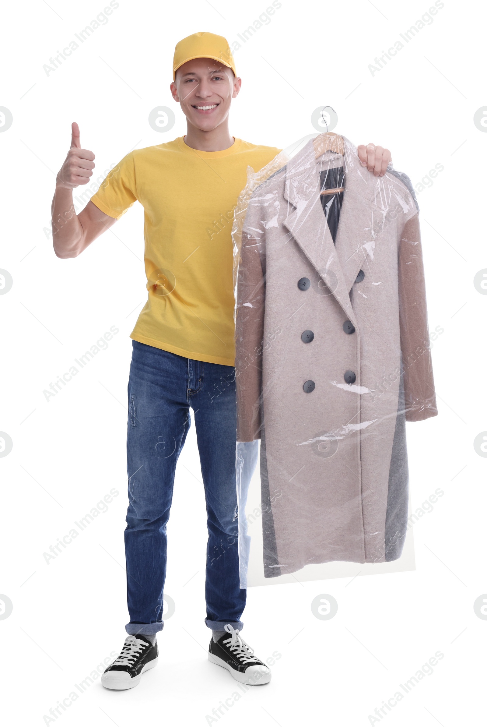 Photo of Dry-cleaning delivery. Happy courier holding coat in plastic bag and showing thumbs up on white background