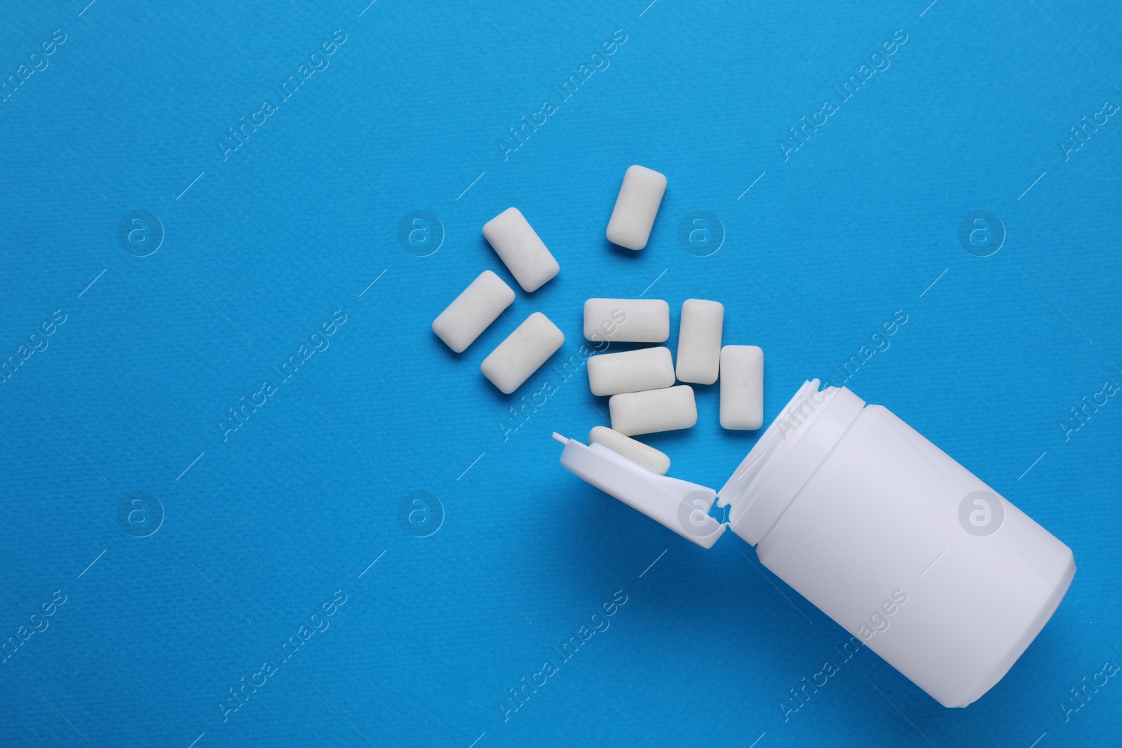 Photo of Jar with chewing gums on light blue background, flat lay. Space for text