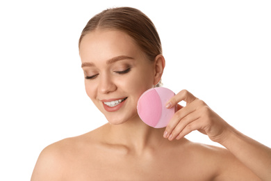 Young woman washing face with cleansing brush on white background. Cosmetic product