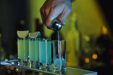 Photo of Bartender pouring alcohol drink into shot glass on blurred background, closeup. Space for text