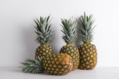 Photo of Whole ripe pineapples on white wooden table