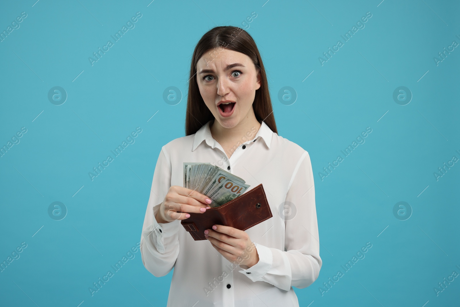 Photo of Woman putting money into wallet on light blue background