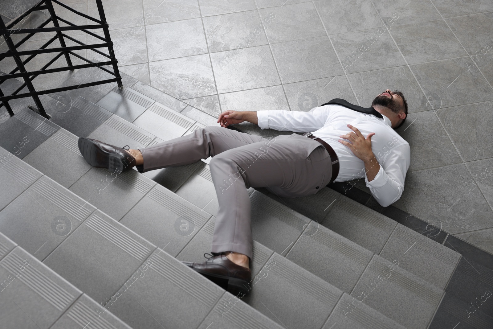 Photo of Unconscious man lying on floor after falling down stairs indoors